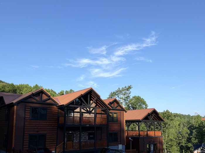 A row of completed cabins with timber-frame gables and standing-seam metal roofs on a finished drive.